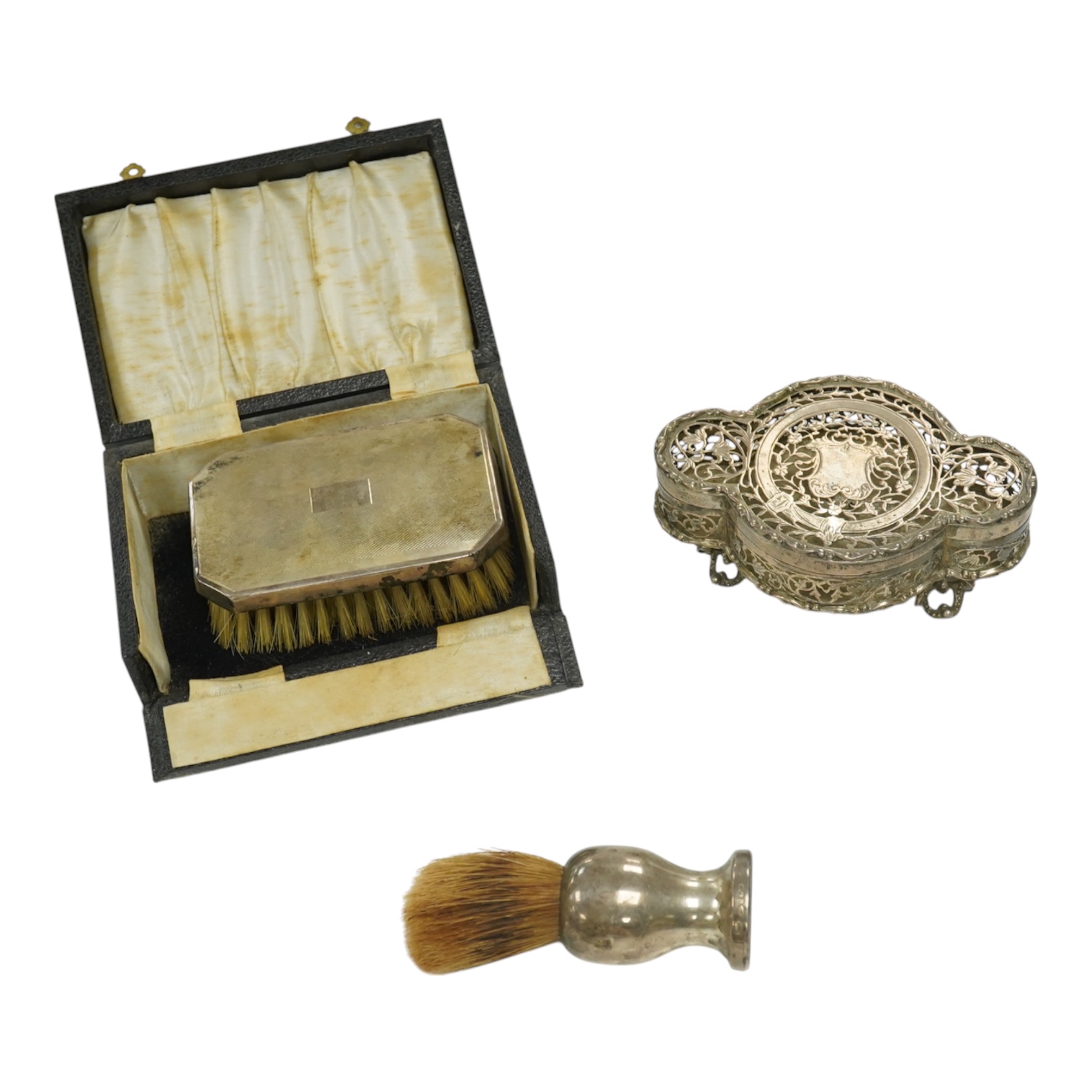 A George V pierced silver pot pourri box, by Nathan & Hayes?, Birmingham, 1916, 13.2cm, together with a silver mounted shaving brush and a cased silver mounted clothes brush. Condition - fair